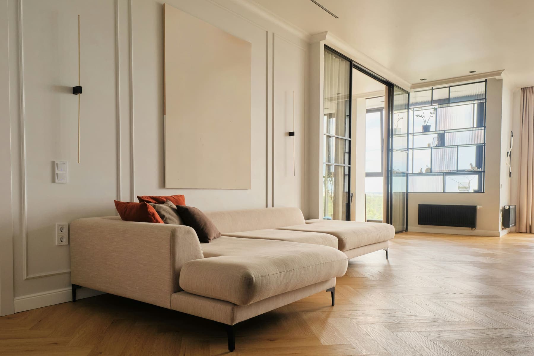Beige sectional in panelled room with herringbone floor